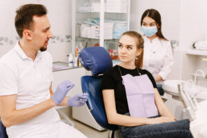 Dentistry. The dentist and his assistant are talking to the patient. The patient is sitting in a chair.